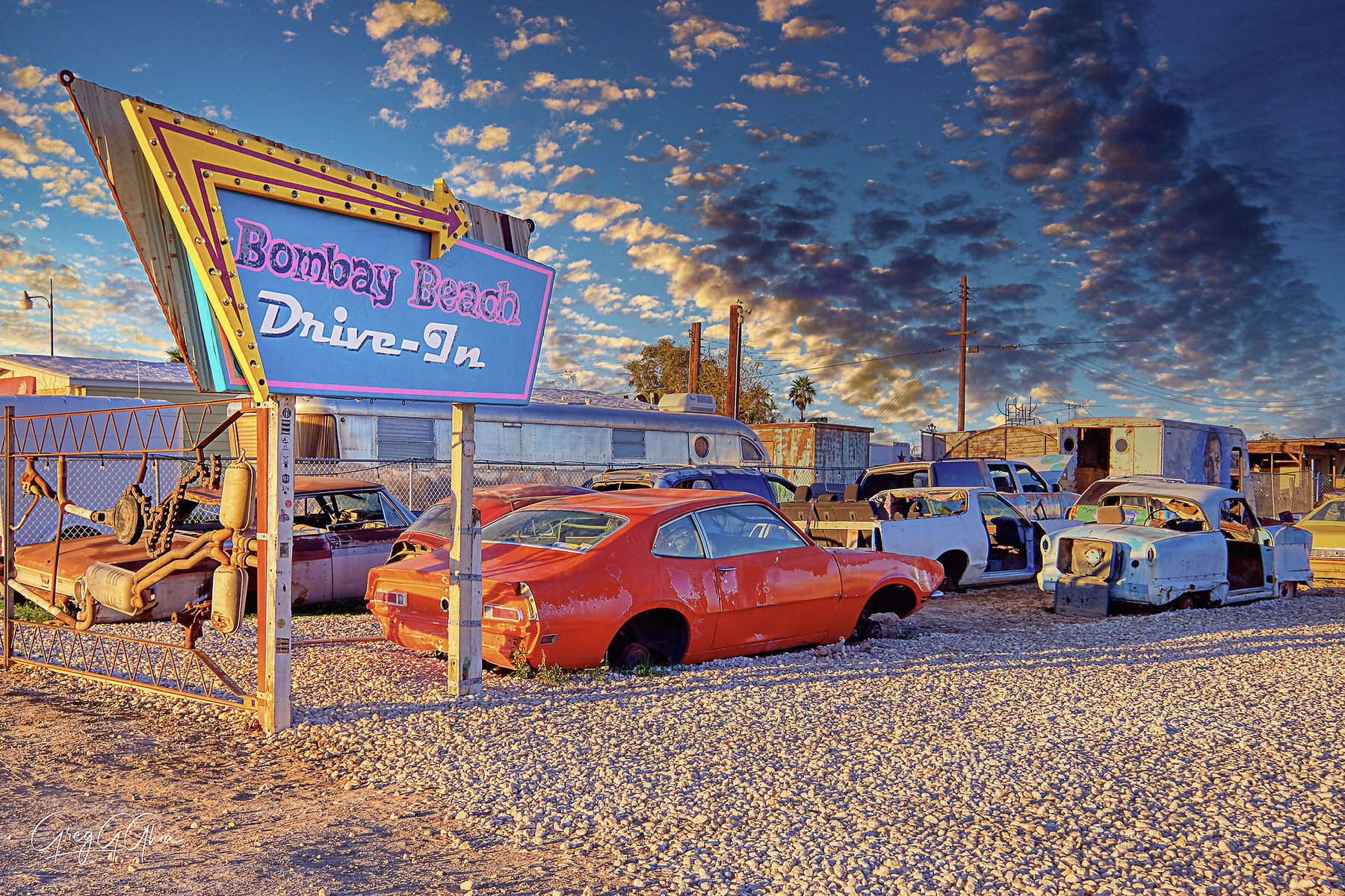 Bombay Beach Drive In is shown with vintage cars in the parking lot with the neon marquee sign and bold letters for a classic vintage photograph.